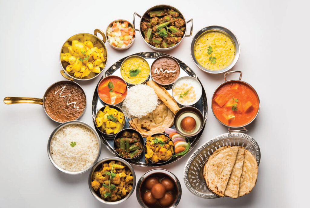 Indian cuisine spread out on white background: biryani, tikka masala with chutneys and more.