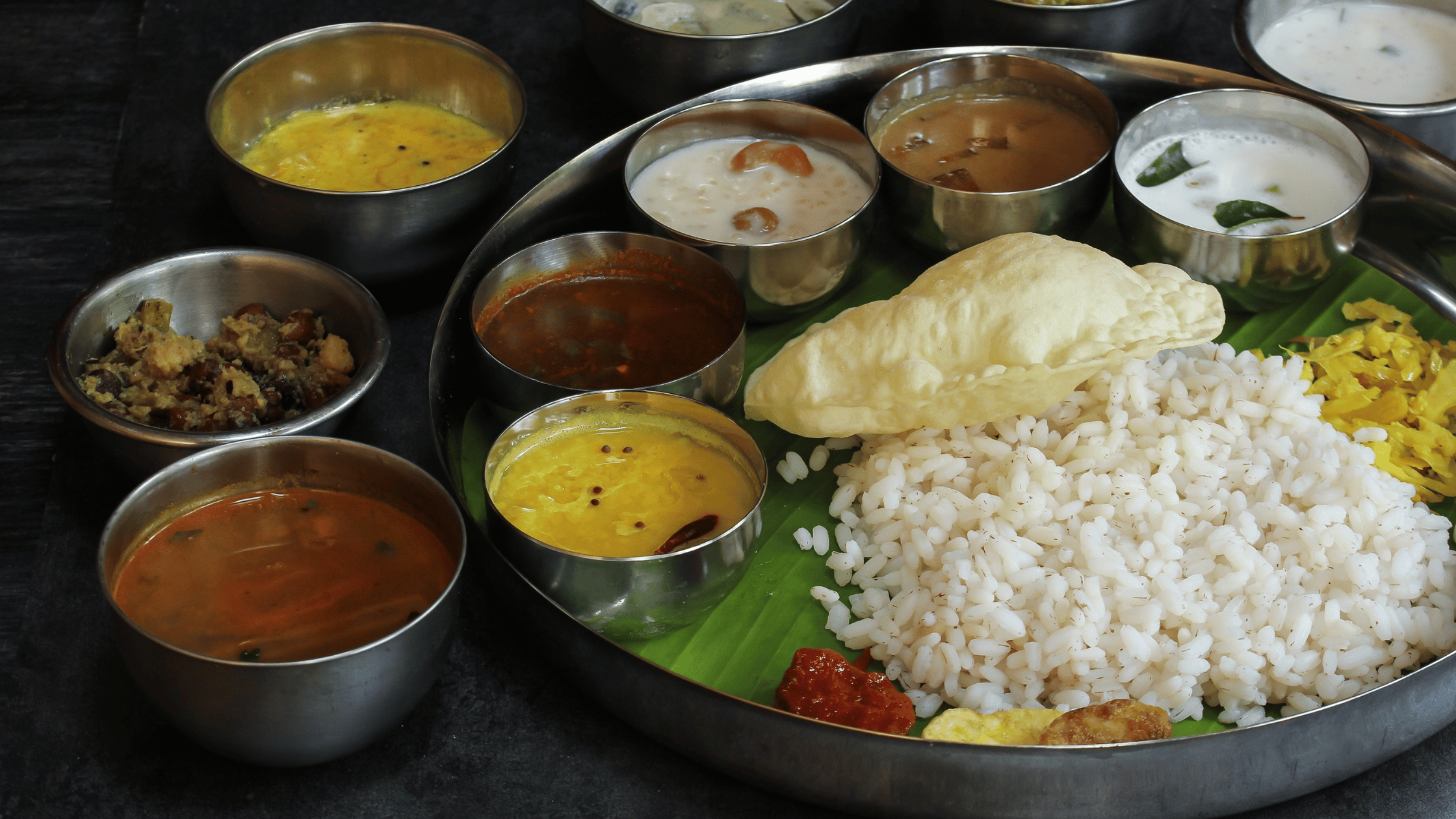 Authentic South Indian thali served on a banana leaf at Kuppanna, featuring a variety of traditional dishes, rice, papad, and flavorful accompaniments.