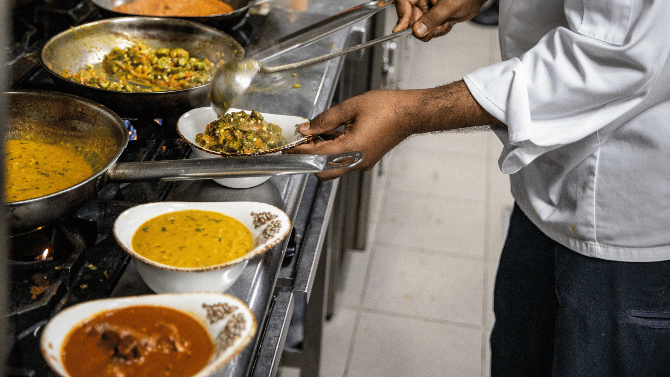 Chef preparing authentic Indian cuisine with rich, flavorful curries and freshly cooked dishes at a restaurant kitchen. A showcase of traditional culinary excellence.