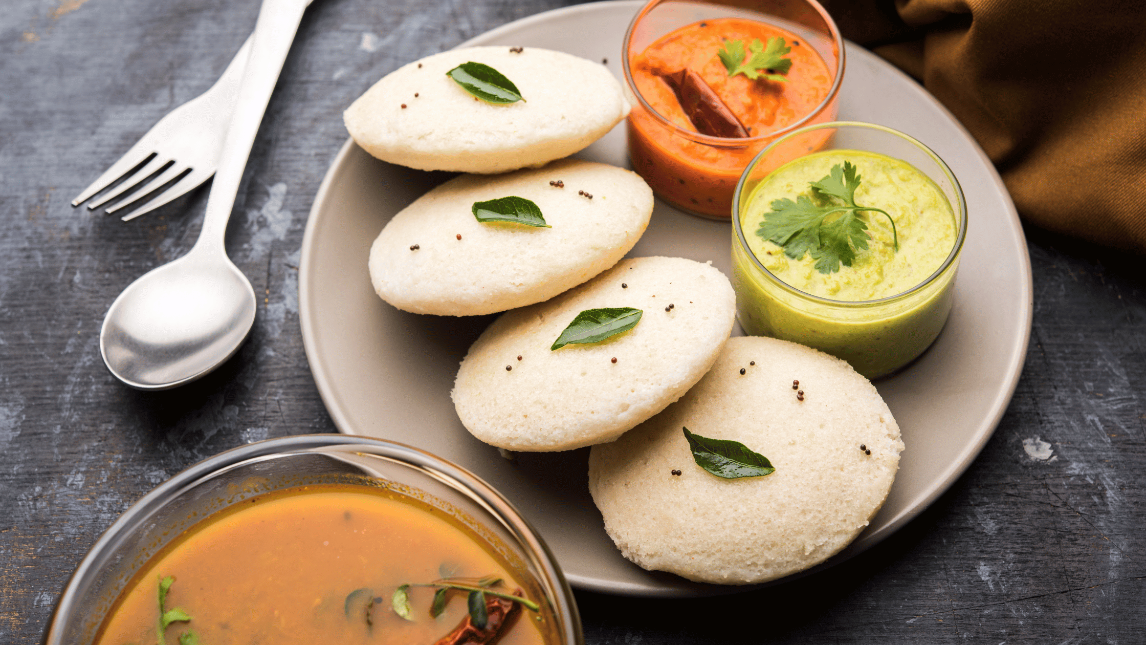 Traditional South Indian breakfast of idli served with sambar, coconut chutney, and tomato chutney – authentic Indian food in Austin