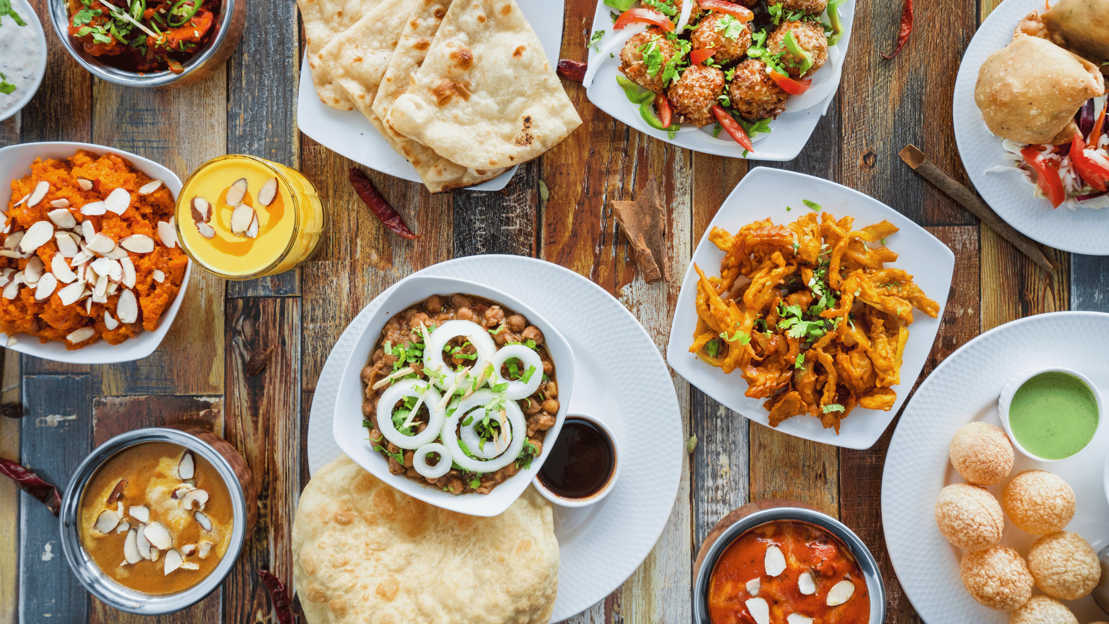 Best Indian food in Texas featuring chole bhature, paneer curry, pakoras, naan, gulab jamun, gajar halwa, and mango lassi – vibrant North Indian cuisine spread