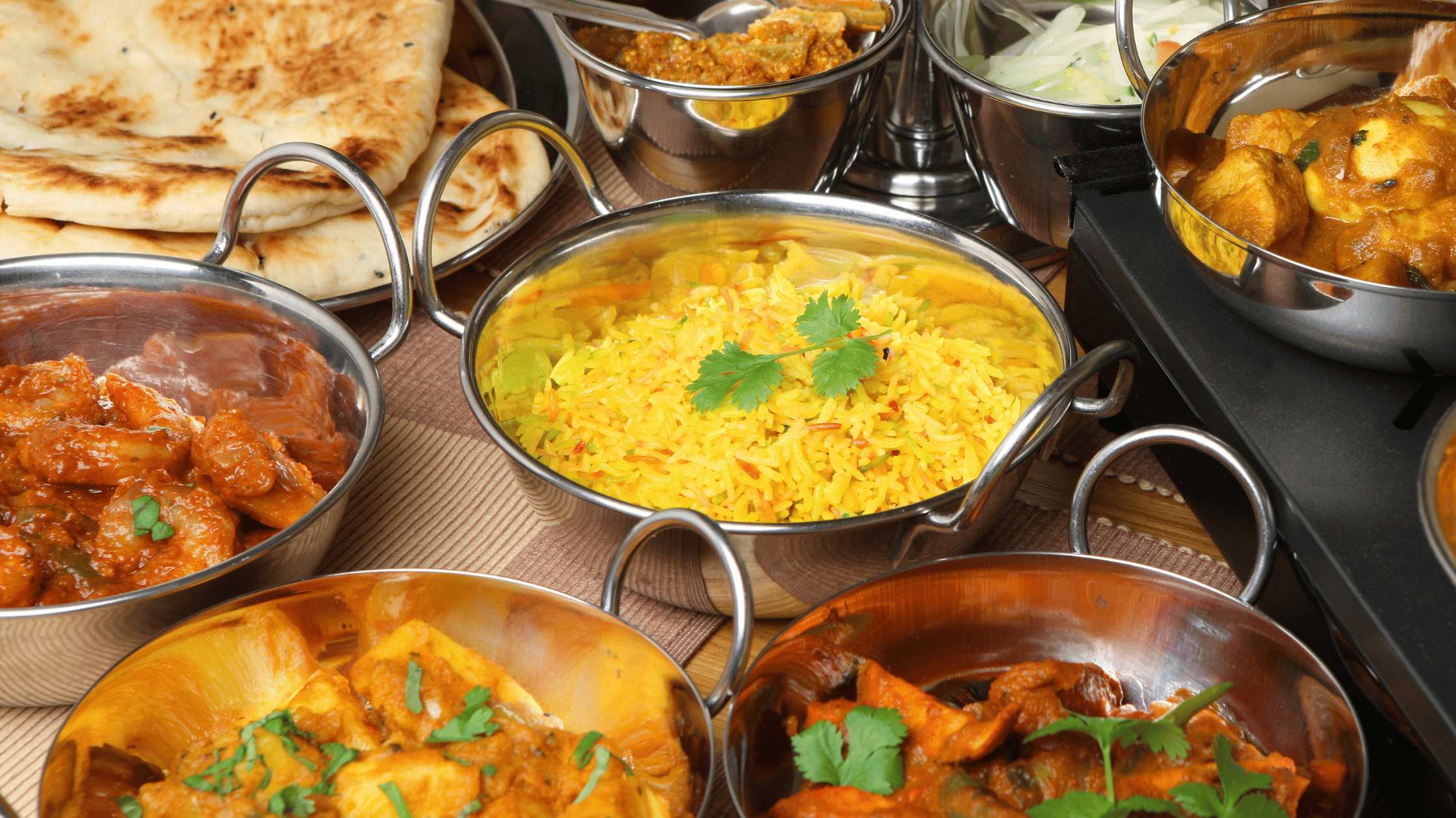 Delicious Indian thali with naan, saffron rice, paneer curry, and spicy gravies served at Kuppanna Indian Restaurant in Austin