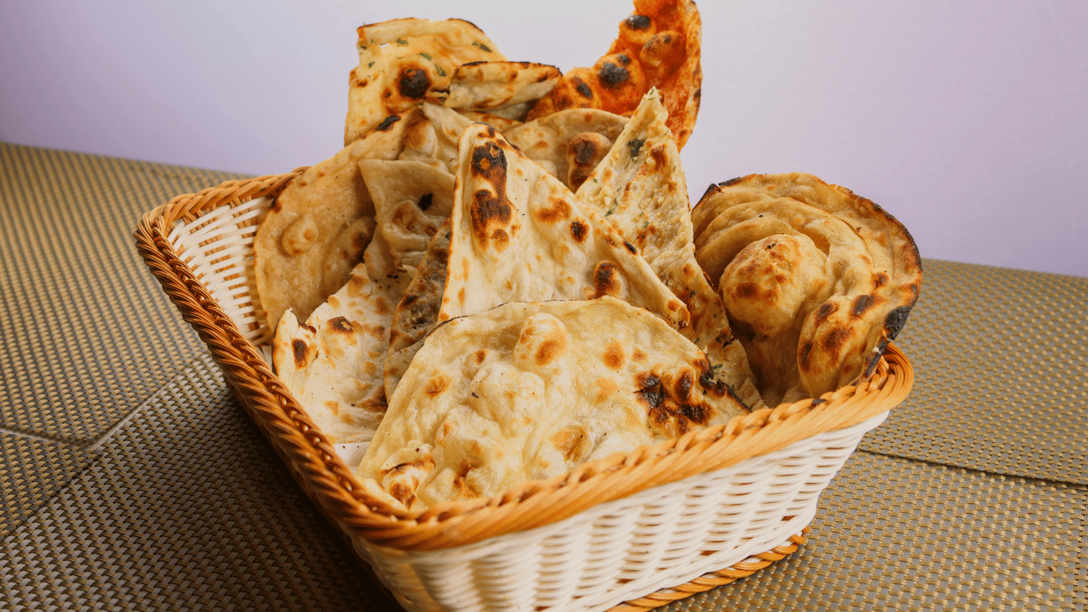 Assorted Indian naan breads served in a basket at Kuppanna Indian Restaurant in USA